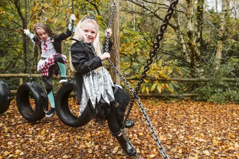 Children in Halloween costumes on a rope swing