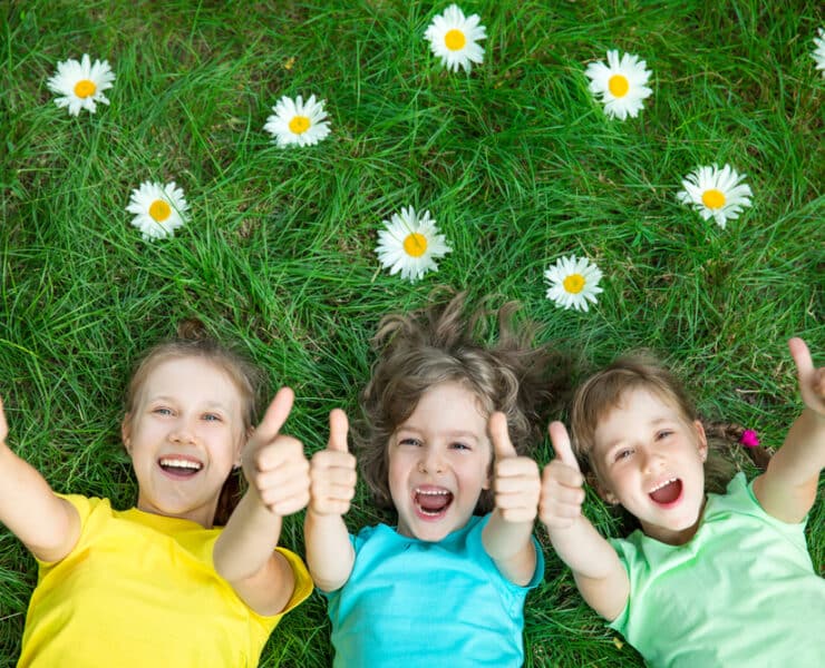 kids in grass sticking thumbs up and smiling