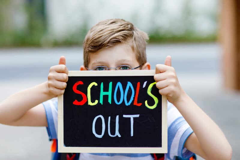 boy holding up schools out sign