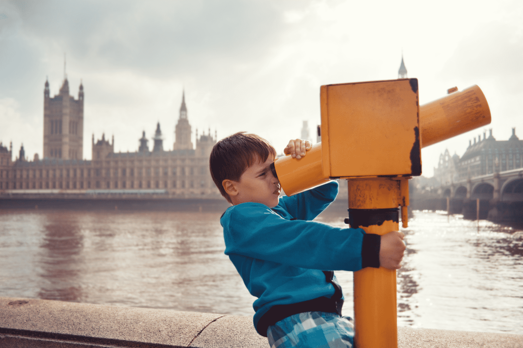 Boy looking through yellow telescope at the house of commons