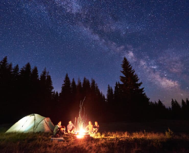 family camping at night time with campfire