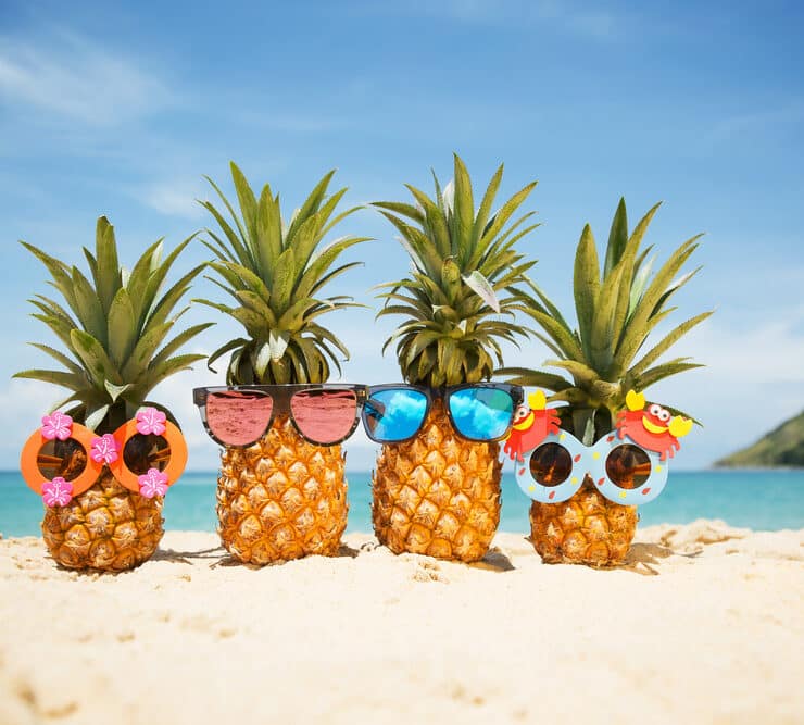 pineapples wearing sunglasses on the beach