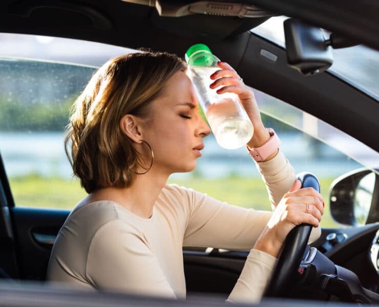 woman holding a water bottle to her head