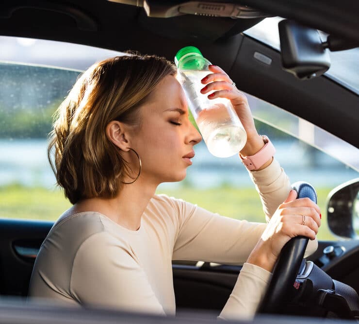 woman holding a water bottle to her head