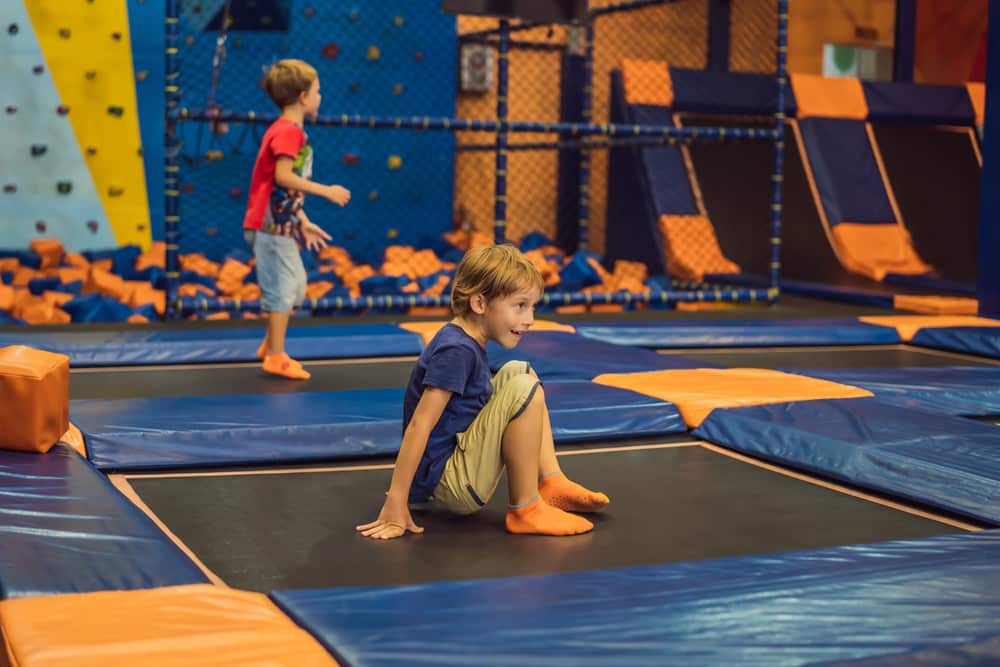 boy sitting on a trampoline at a trampoline park