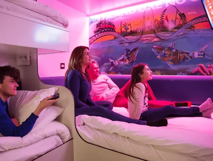 family sitting on bed with pink lighting in the Shark Hotel