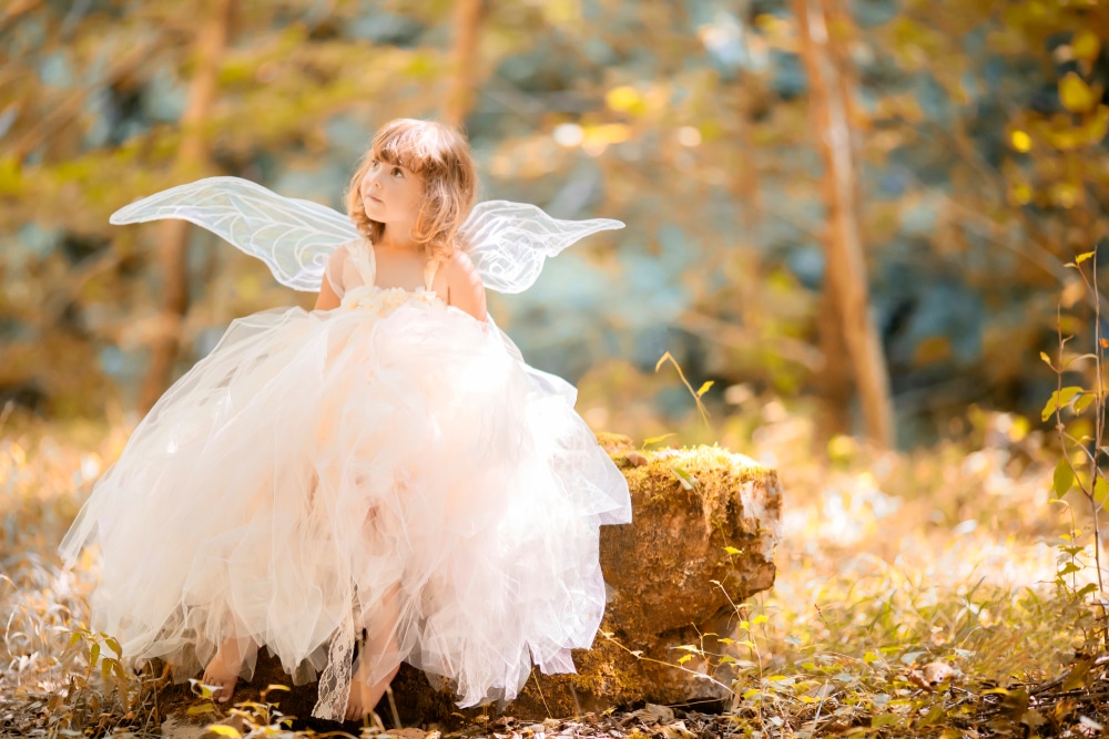 a little girl dressed as a fairy in the forest