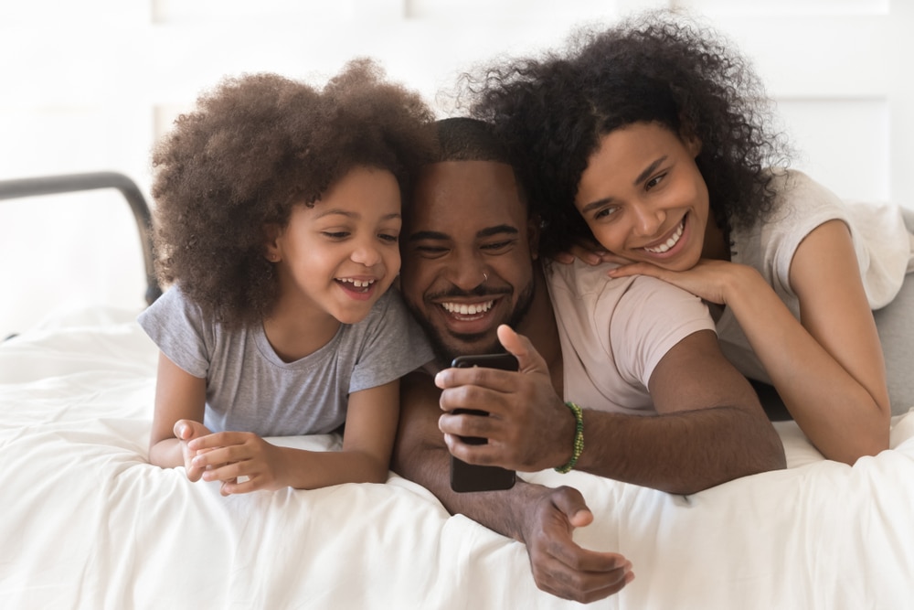 a family of three on a bed in a hotel room