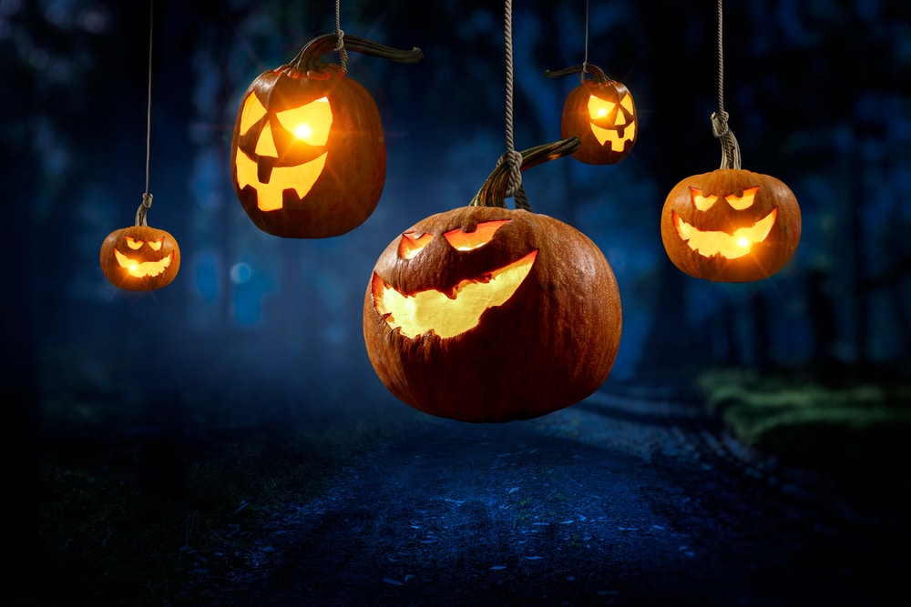 5 pumpkins in the air with candles inside and they are showing an evil smile