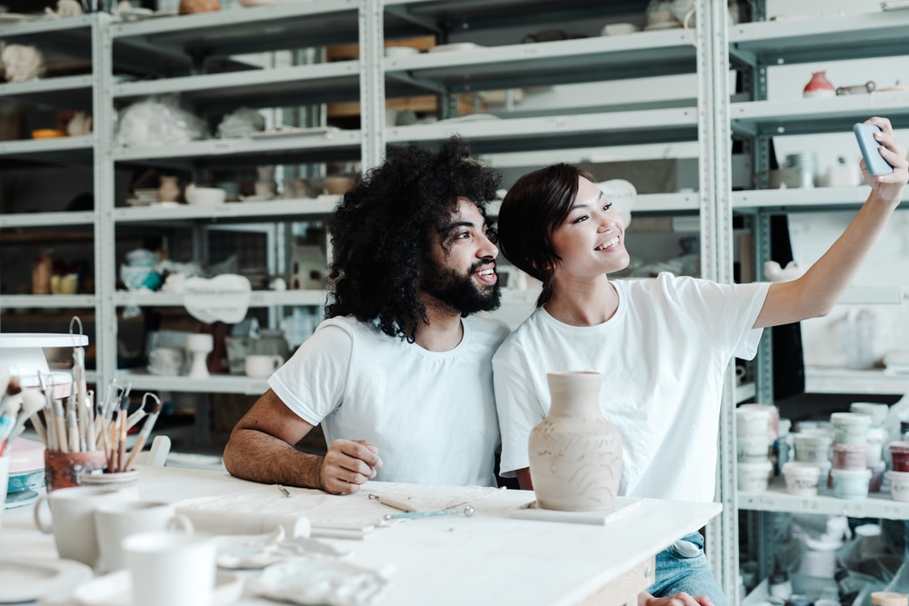 adults taking a selfie whilst pottery painting