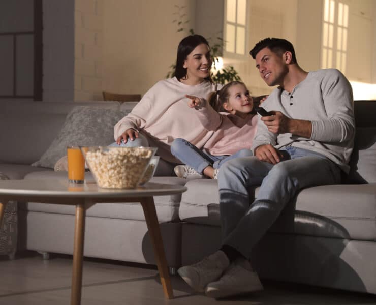 a family of 3 eating popcorn and watching a film