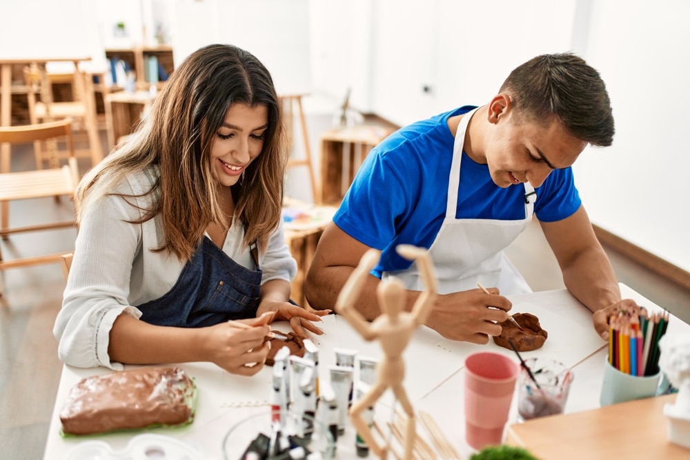 two adults painting pottery