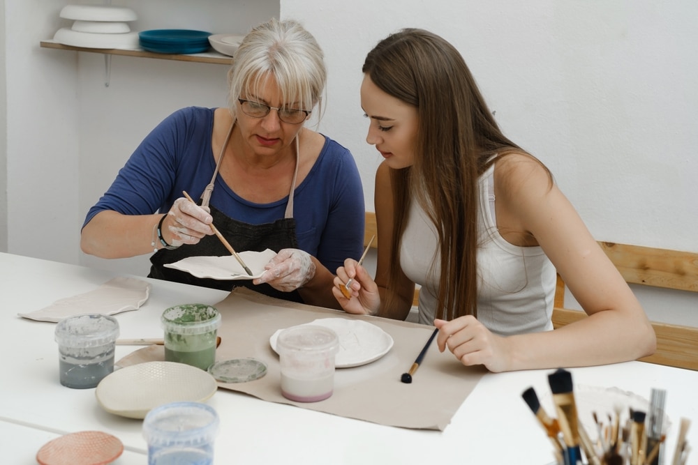 adults painting pottery