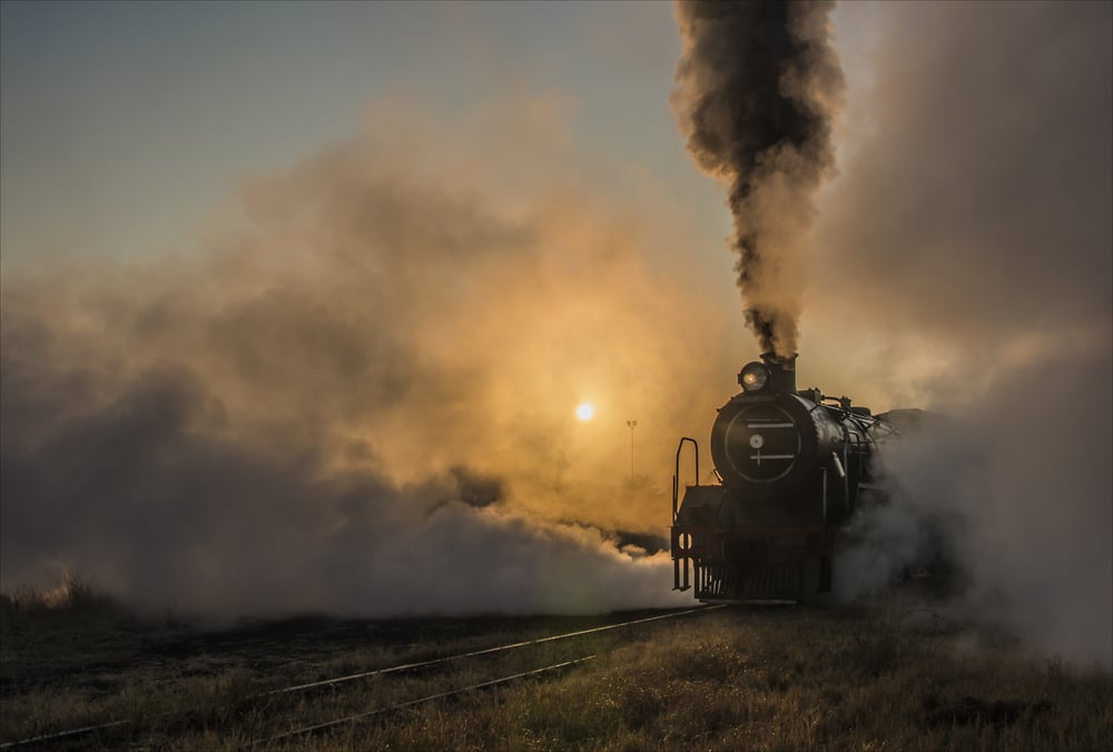 steam train travelling with the sunset in the background