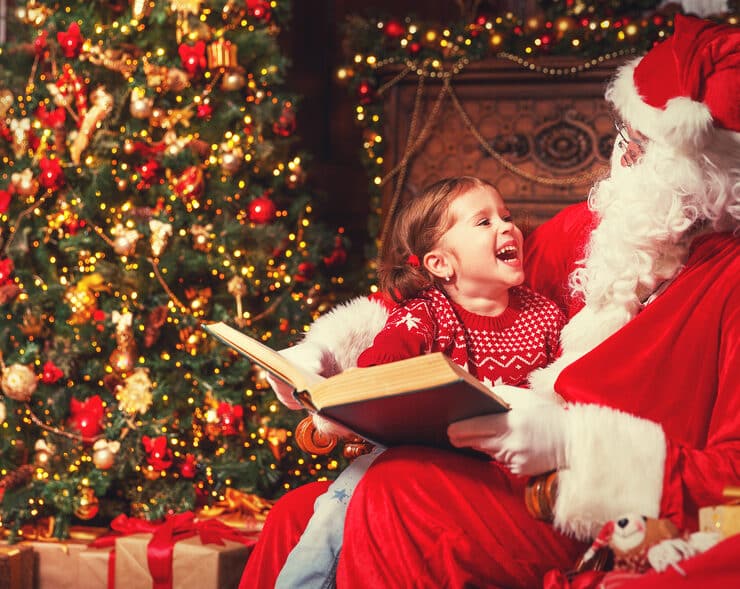 santa and a little girl by a christmas tree