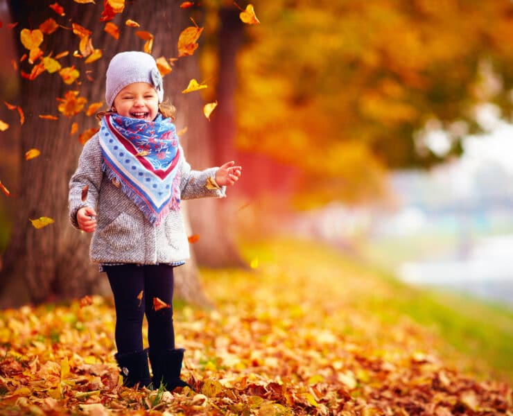 little girl playing in autumn leaves