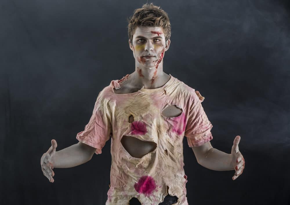 man dressed up as a zombie with ripped clothes and red paint