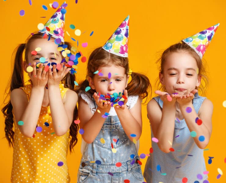 kids wearing party hats and blowing confetti