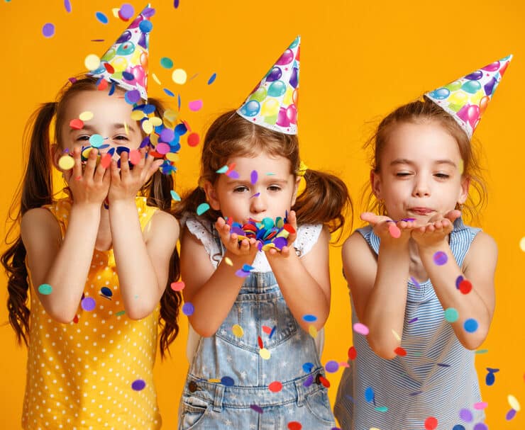 kids wearing party hats and blowing confetti