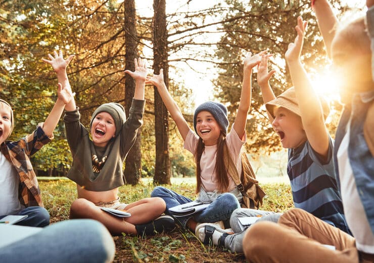 a group of kids on the forest floor having a good time