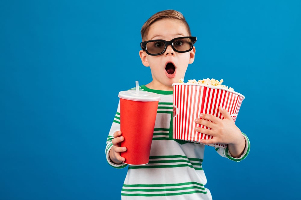 child holding a popcorn tub and big drink