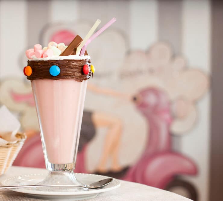 a strawberry milkshake with smarties along the rim and chocolate