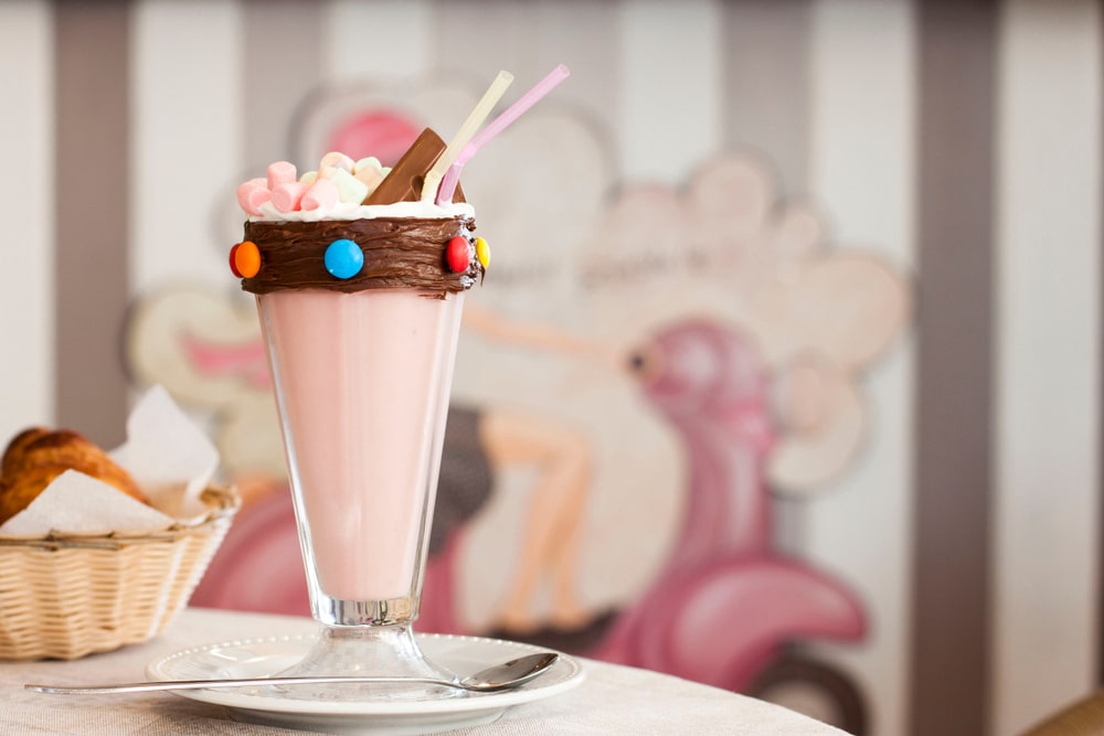 a strawberry milkshake with smarties along the rim and chocolate