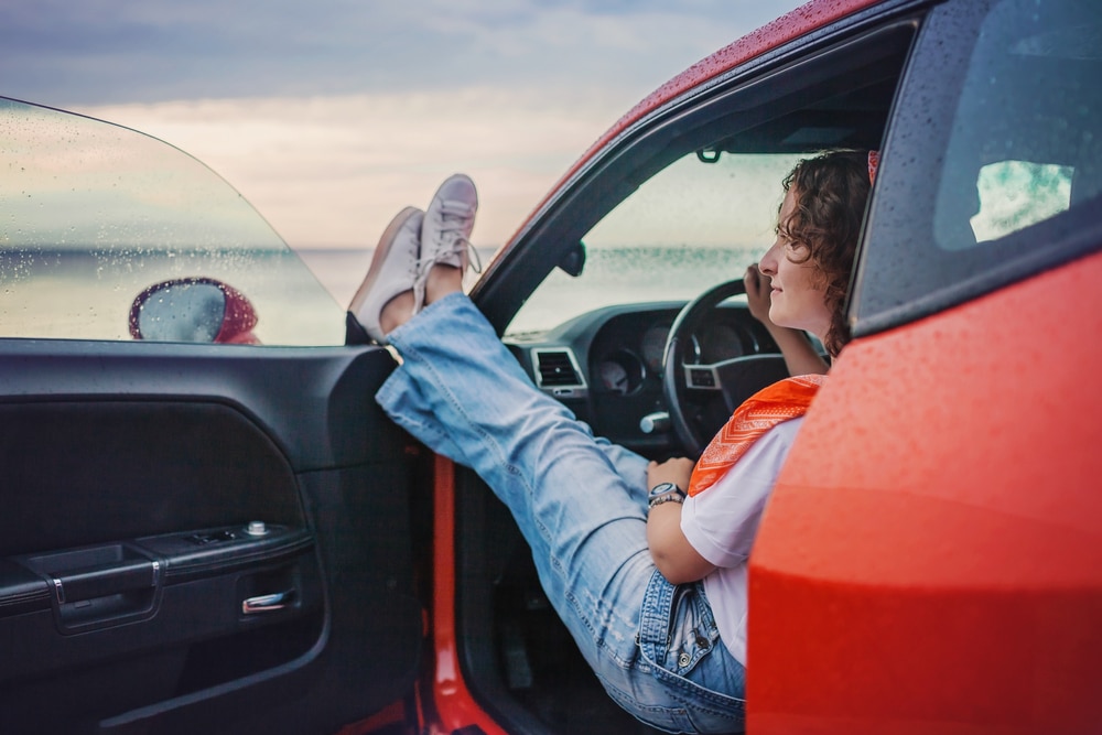 someone resting in a car by the sea