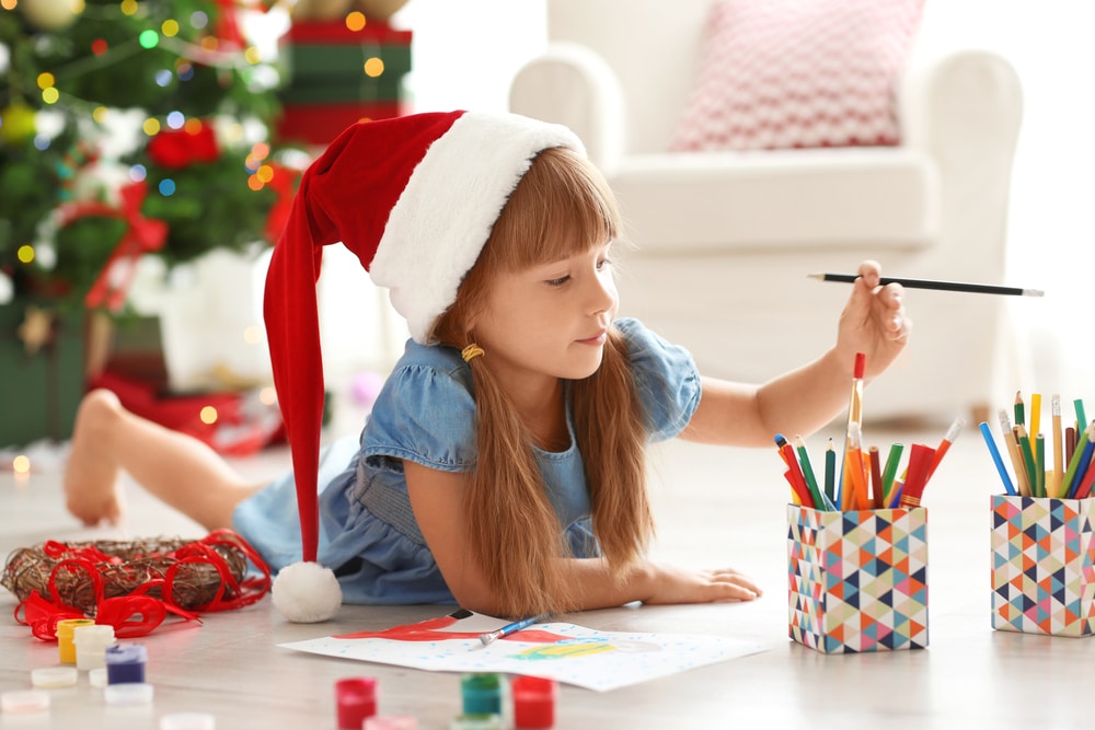 little girl wearing a santa hat colouring in