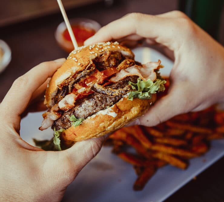 someone holding a burger with fries on the side
