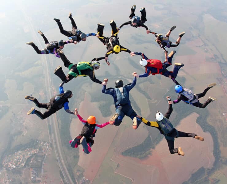 a group of people skydiving together holding hands and feet