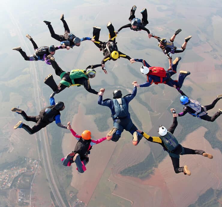 a group of people skydiving together holding hands and feet