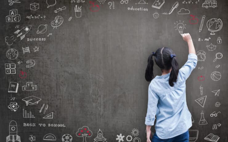 girl writing on a chalkboard with inspirational drawings