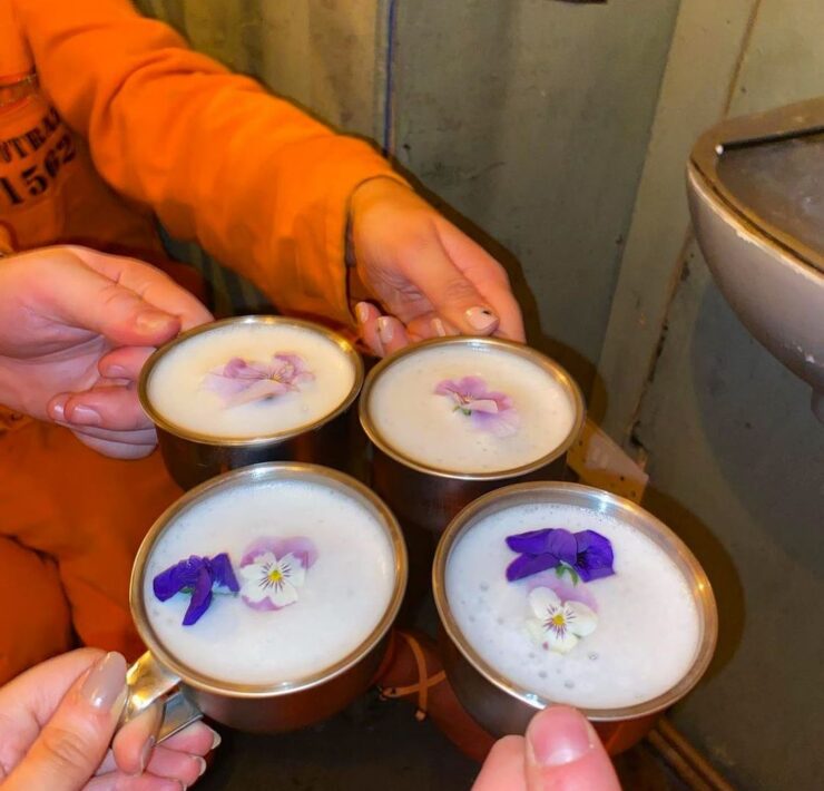 white cocktails served in metal jugs with violets on top