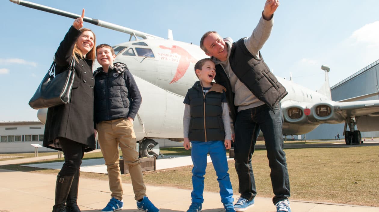 parents pointing to sky and talking to their children next to an aeroplane