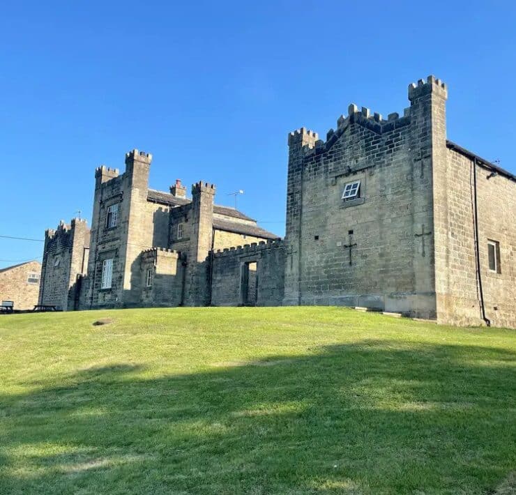 historic stone building mounted on grass hill. Peak district airbnb