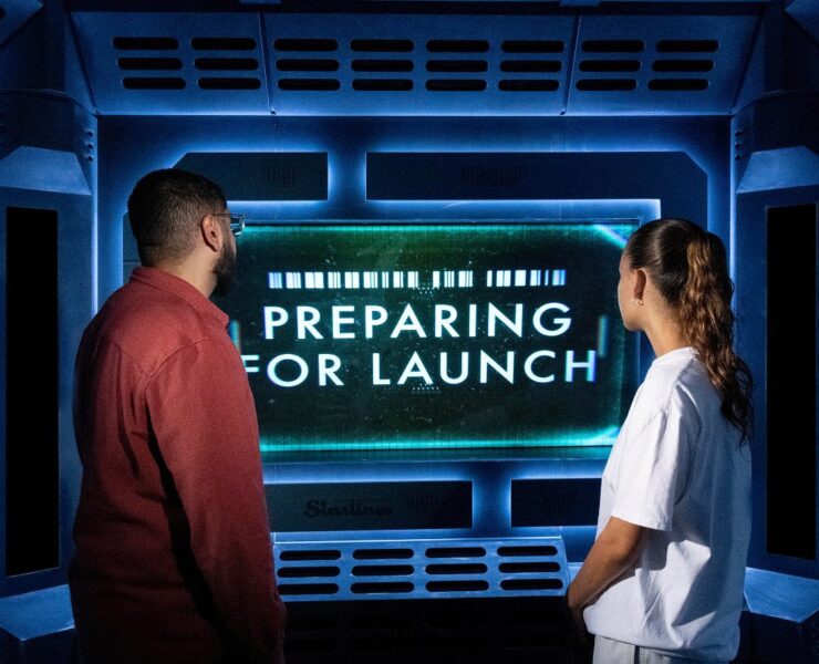 two people staring at a large flat screen TV in the Science Museum: Voyage To The Edge Of Imagination exhibition