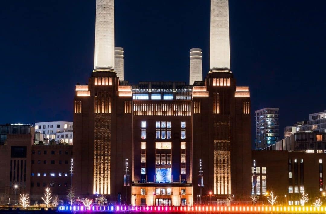 battersea power station lit up in colourful lights at night time