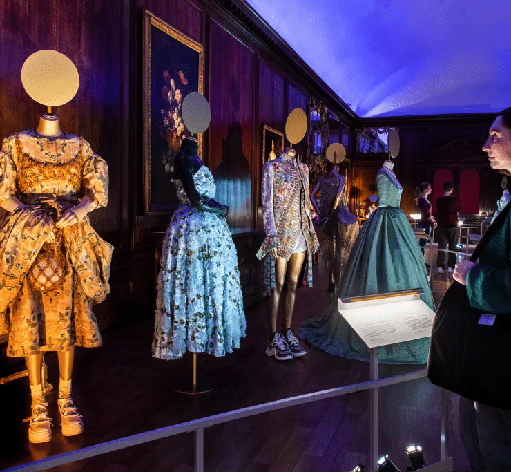 woman looking at dresses from history in the crown to couture exhibitition