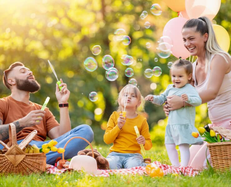 dad blowing bubbles at kids on family picnic