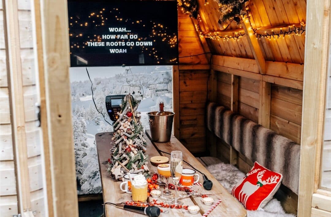 karaoke machine, bottle of champagne on ice, christmas cushions, fur and jugs of hot chocolate inside a bar hutte