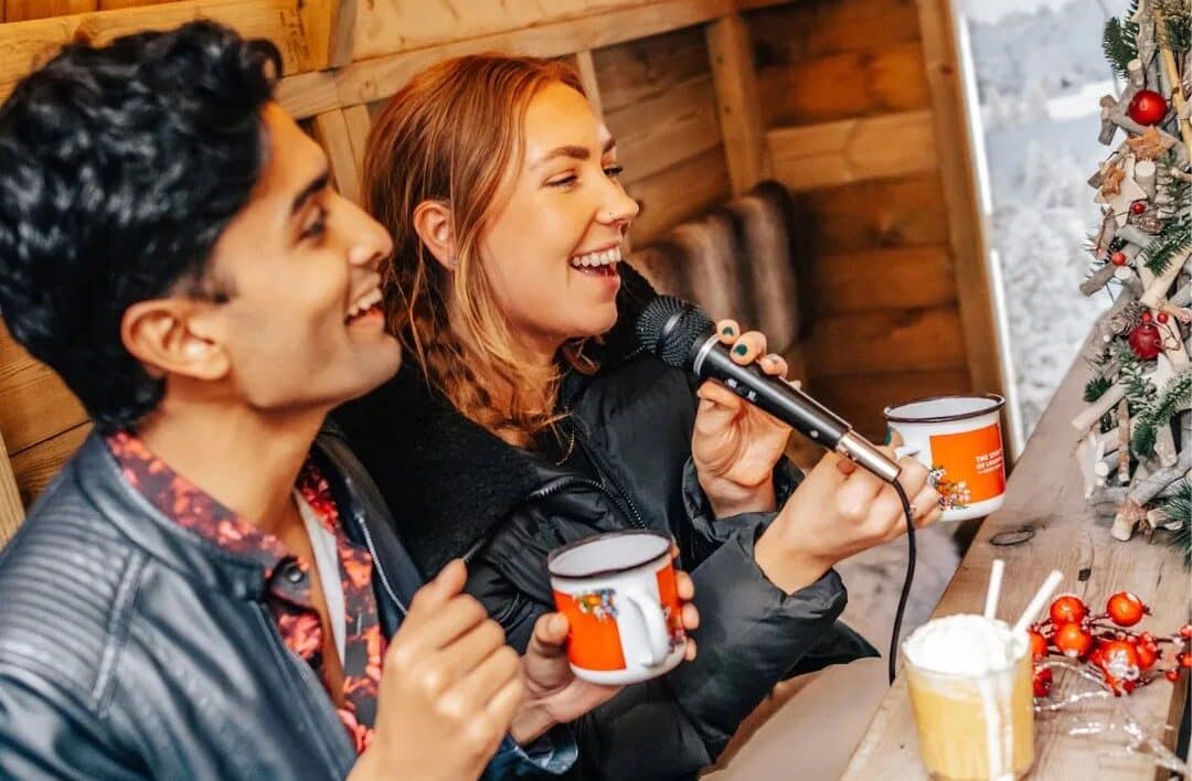 young woman and man doing karaoke while holding a mug of hot chocolate