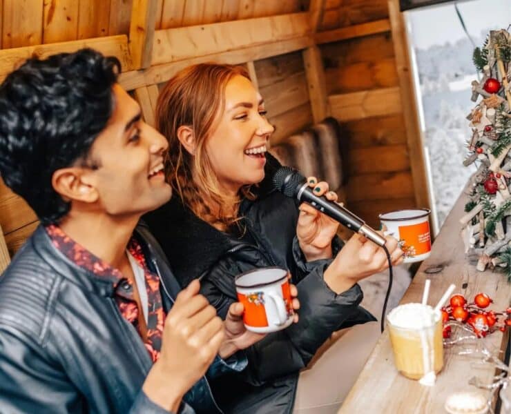young woman and man doing karaoke while holding a mug of hot chocolate