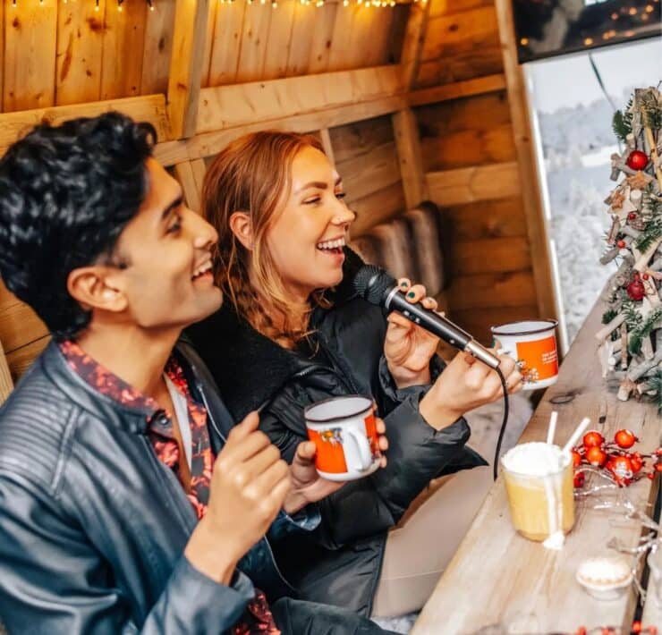 young woman and man doing karaoke while holding a mug of hot chocolate