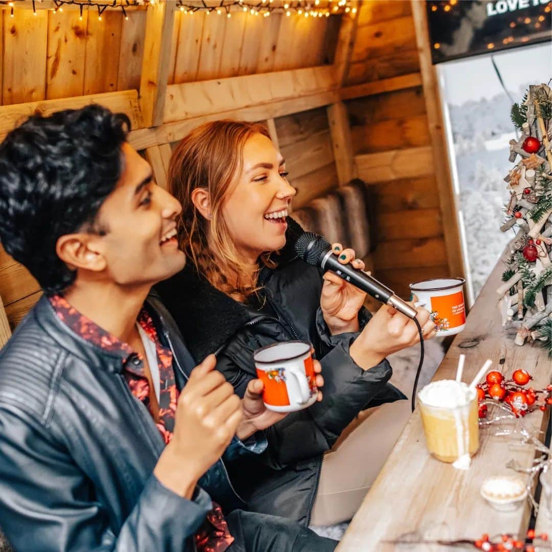 young woman and man doing karaoke while holding a mug of hot chocolate