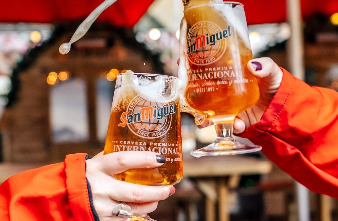 two workers toasting san miguel pints outside alpine hut