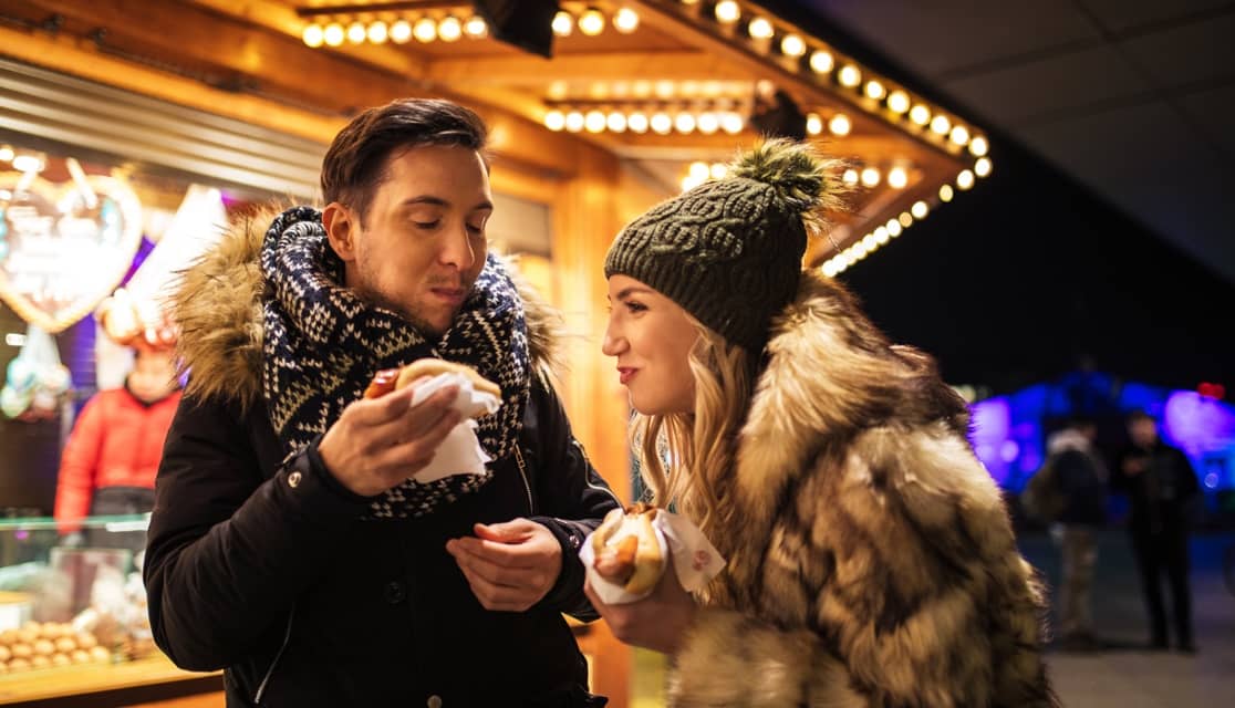 a couple eating food from stalls