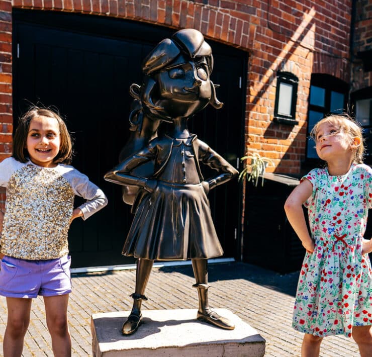 two girl posing next to matilda sculpture at roald dahl museum