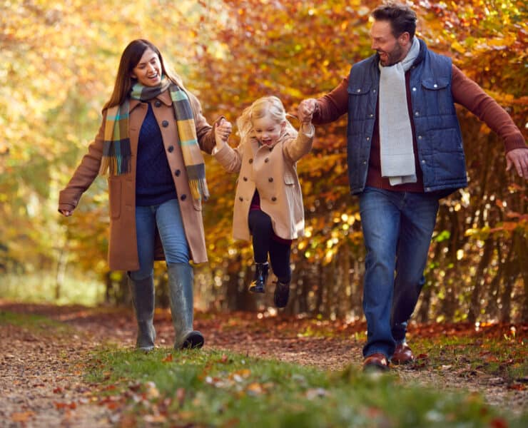 family skipping in autumn leaves