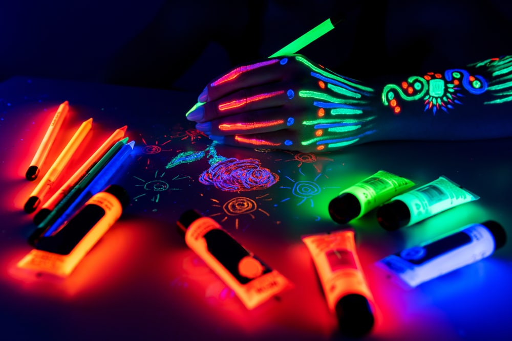 person drawing with UV pencils and paints